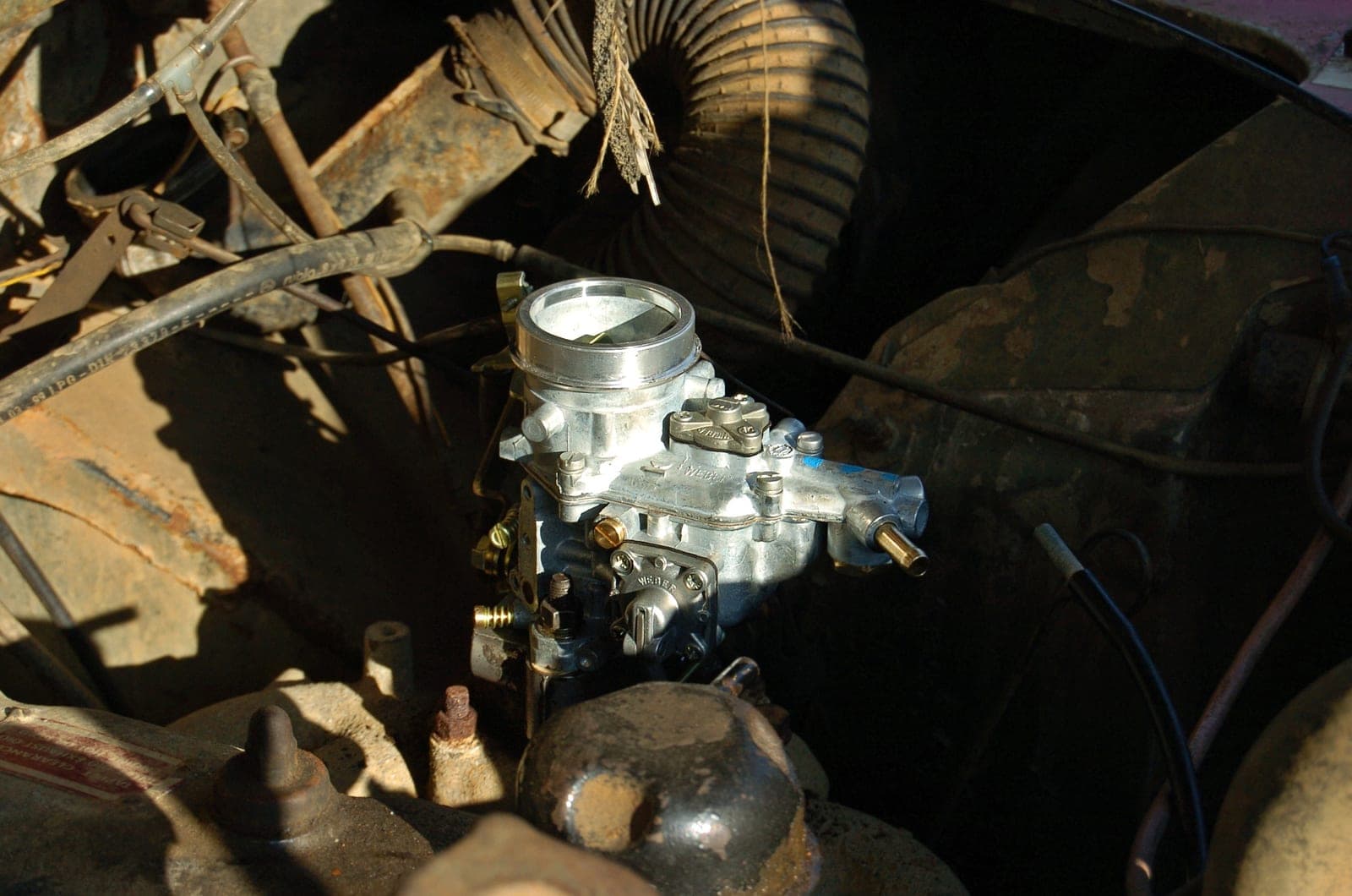 Carburateur Weber sur un moteur ancien, dans un compartiment moteur encrassé